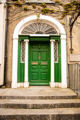 A green door with columns in a street of row homes in Ireland