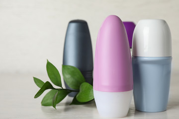 Natural roll-on deodorants and green plant on light grey table