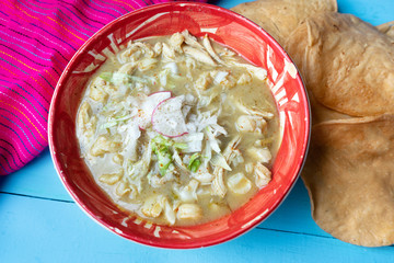 Mexican green pozole soup on blue background