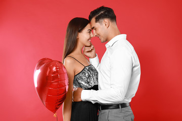 Beautiful couple with heart shaped balloon on red background