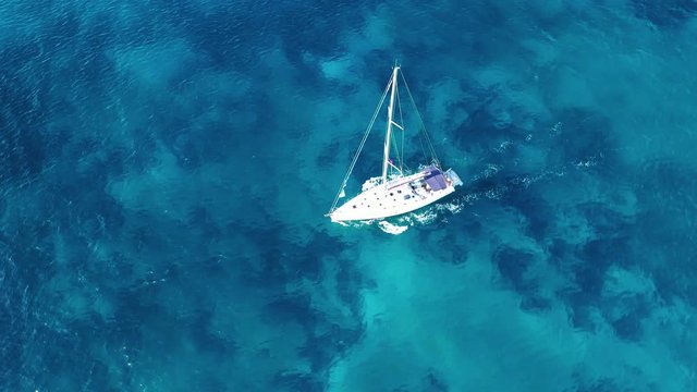 Aerial drone birds eye view video of beautiful sail boat cruising in the deep blue Aegean sea, Greece