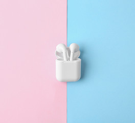 Modern wireless earphones in charging case on color background, top view