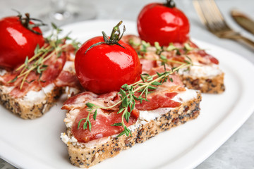 Plate of delicious bruschettas with prosciutto on grey table, closeup