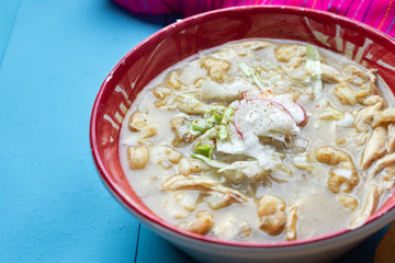 Mexican green pozole soup on blue background