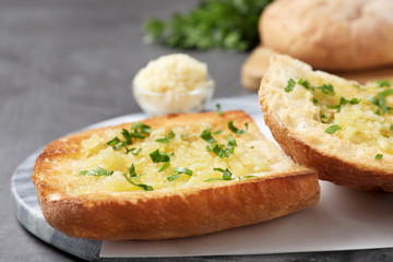 Slices of delicious toasted bread with garlic and herbs on grey table, closeup