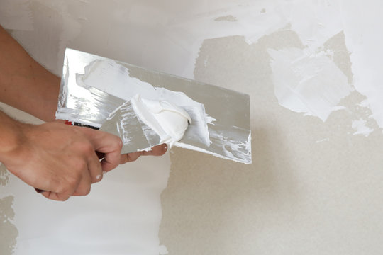 Process of plastering wall with putty-knife. Fixing wall surface and preparation for painting, home renovation concept