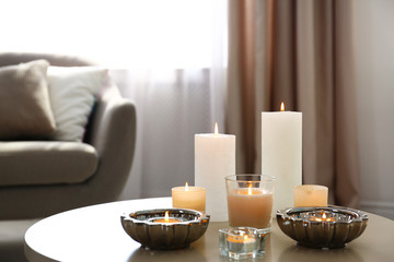 Burning decorative candles on table in room