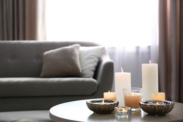 Burning decorative candles on table in room