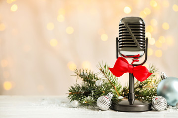 Microphone with red bow and decorations on white table against blurred lights, space for text....
