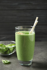 Glass of healthy green smoothie with fresh spinach on grey table