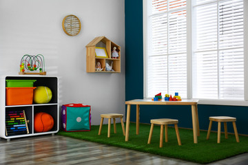 Stylish playroom interior with wooden table and stools