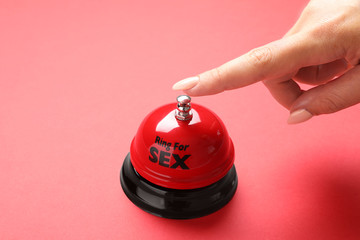 Young woman with sex bell on red background, closeup