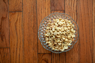 Peanuts in a vintage glass dish on wood background