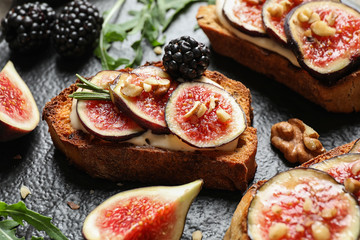 Bruschettas with cream cheese, figs and blackberries on slate plate, closeup