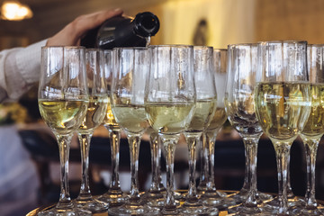 The waiter pours champagne into the glasses, preparing for the banquet. Welcome drink