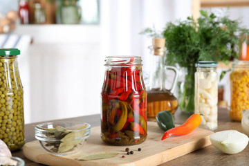 Jar with pickled chili peppers on wooden table indoors