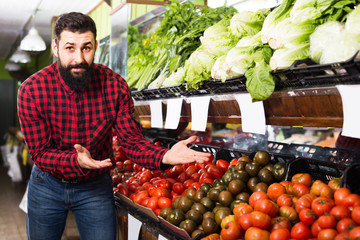 Fototapeta premium Glad man seller offering tomatoes in shop