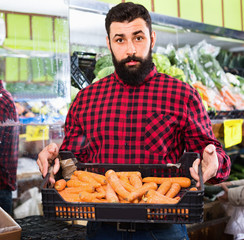 Young male seller offering carrots