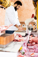 Male shop assistant carving meat