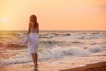 Beautiful young woman on beach at sunset