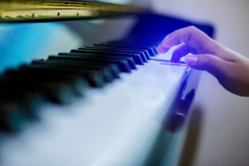 Selective focus to piano key with hand kid press it to play music. Musical instrument for learning music.