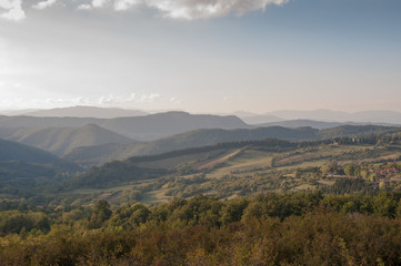 Fototapeta na wymiar Vast countryside landscape with mountains and field on sunset, sunrise
