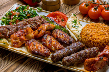 assorted kebabs with bulgur and vegetables Turkish cuisine on wooden table - obrazy, fototapety, plakaty