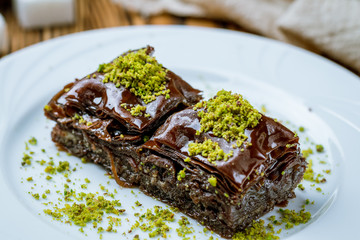 chocolate baklava with pistachios on wooden table. Turkish cuisine