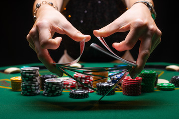 Girl dealer or croupier shuffles poker cards in a casino on the background of a table, chips,....