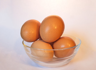 Brown eggs in transparent bowl with drops of moisture from condensation.