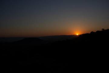 Dawn in the mountains. Mountain landscape. The sun rises from the horizon. Beautiful background early hours in the highlands. Bright rays shine from afar.