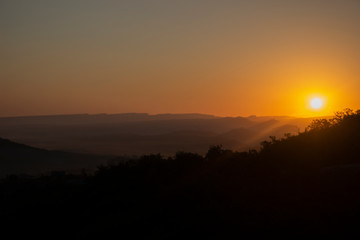 Dawn in the mountains. Mountain landscape. The sun rises from the horizon. Beautiful background early hours in the highlands. Bright rays shine from afar.