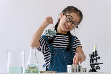 Little 6s cute girl with microscope holding laboratory bottle with water experiment study scientists at school. Education science concept.