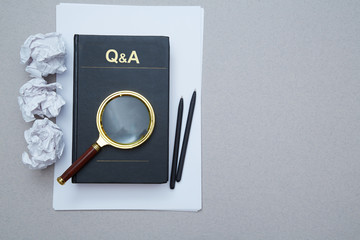 FAQ, Q and A and SEO idea. Question and answer or analysis concept. Magnifying glass, book and crumpled paper