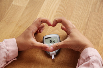 girl folded her fingers over a blood glucose meter for measuring blood sugar, healthcare concept, diabetic, horizontal, closeup, copy space
