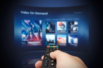 VOD service screen with remote control in hand