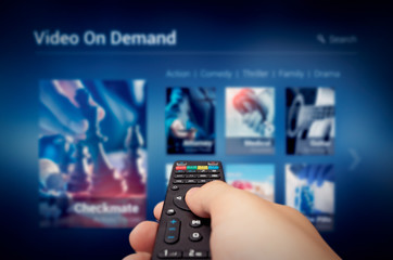 VOD service screen with remote control in hand