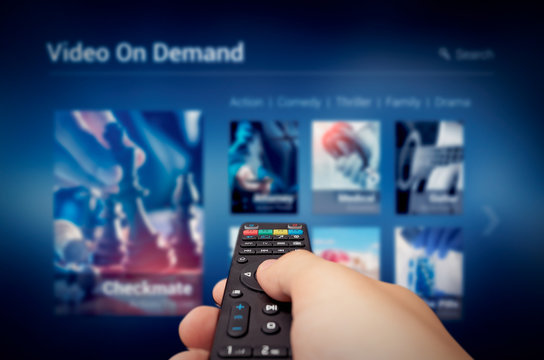 VOD service screen with remote control in hand