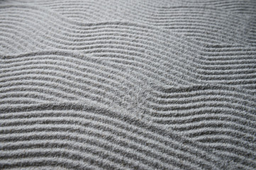 Simple graphic wave patterns raked into a background in the white sand of a Japanese Zen garden