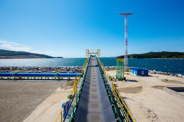Obraz premium The territory of the marine coal terminal. Construction site of a coal terminal. Warehouse with building materials on the seashore.