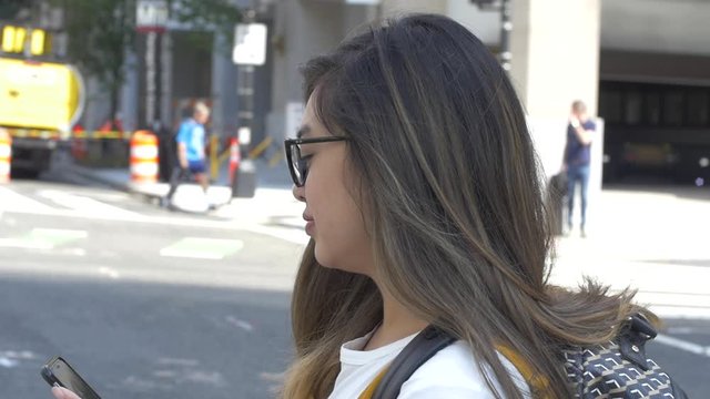 Young Woman Crosses Street in City while Texting Phone