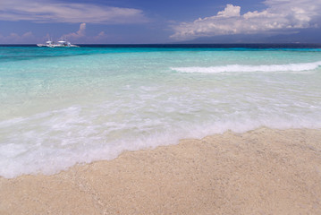 Tropical landscape with  Filipino traditional banka fishing outrigger boat on a white sand beach, beautiful clear turquoise water. Sumilon island, Philippines.