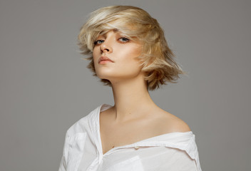 Portrait of beautiful blonde woman in white shirt and fashionable hairstyle - obrazy, fototapety, plakaty
