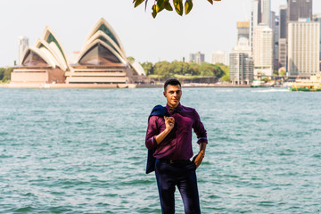 standing by Sydney Harbour and the Opera House in the background, with gum leaves and the Manly Ferry as elements
