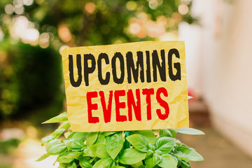 Word writing text Upcoming Events. Business photo showcasing the approaching planned public or social occasions Plain empty paper attached to a stick and placed in the green leafy plants