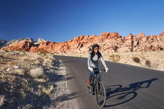 african american woman riding bicycle through red rock canyon park