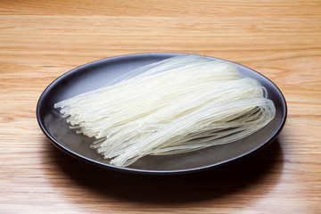 Dried rice noodles in black plate on a wooden table