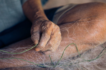 Old fisherman repairing net.Old hand, withered skin