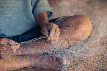 Old hand, withered skin,Fishermen knitting their net ,Close up