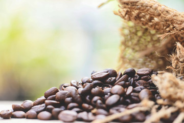 Obraz premium Roasted coffee beans in sack - Closeup macro of coffee beans on wooden and nature sunlight background